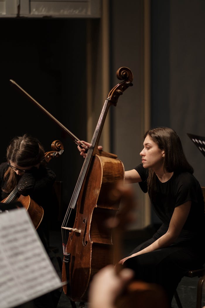 services-04 Woman playing cello during orchestra rehearsal, focusing on performance.